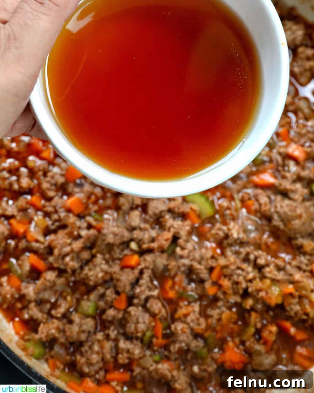 Adding beef broth to the lamb ragu