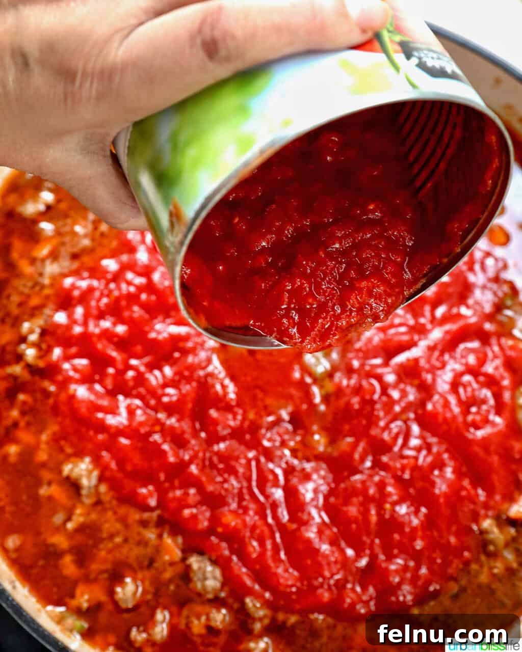 Adding crushed tomatoes to lamb ragu