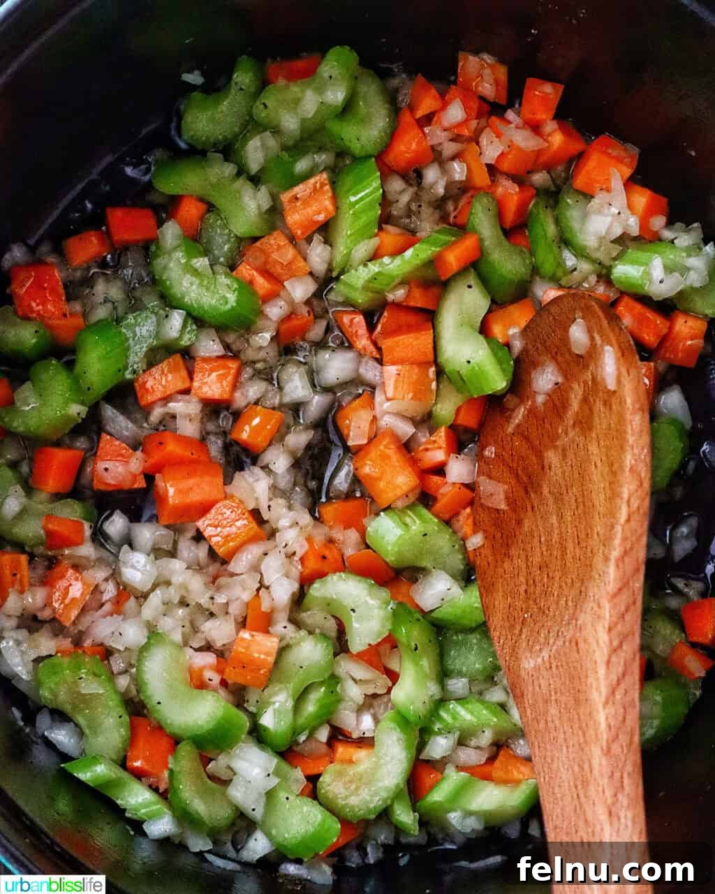 wooden spoon stirring mirepoix of carrots, celery, and onions in a Dutch oven.