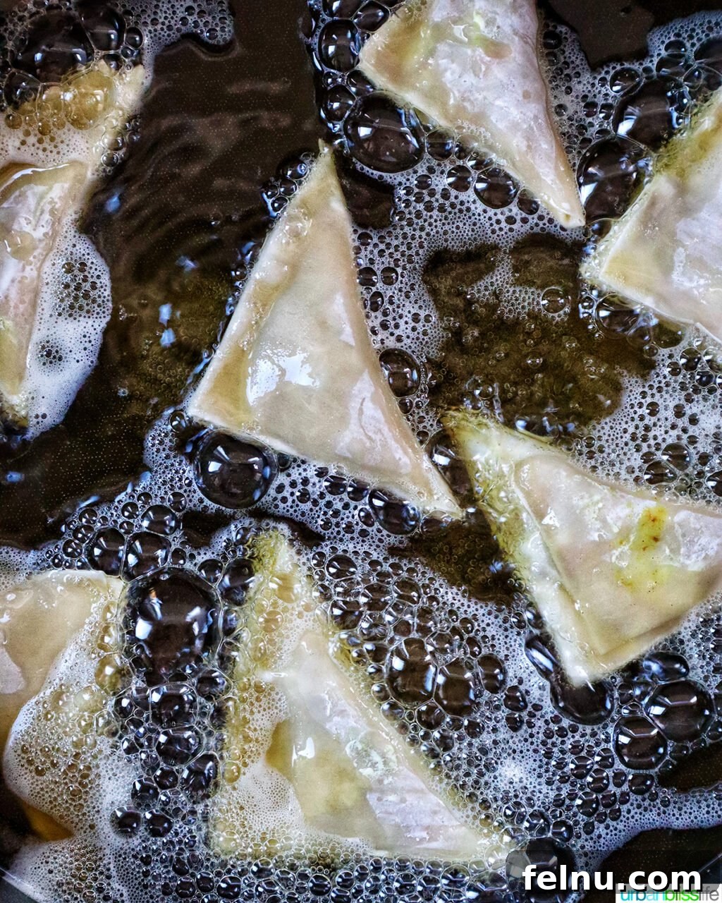 Vegan curry samosas frying in a Dutch oven.