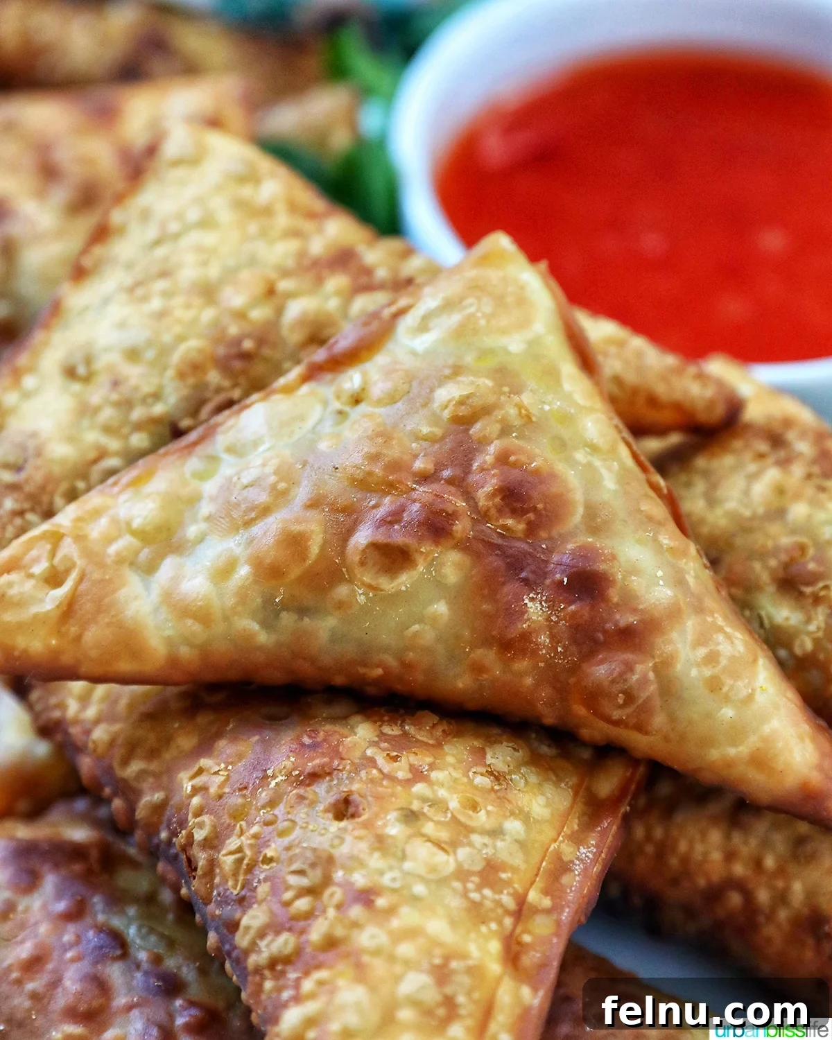Close-up of vegan curry samosas with sweet chili dipping sauce and herb garnish.