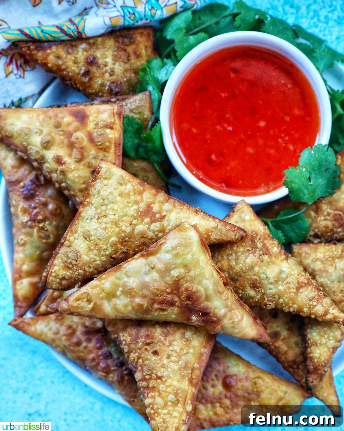 Vegan curry samosas served with sweet chili dipping sauce and herb garnish.