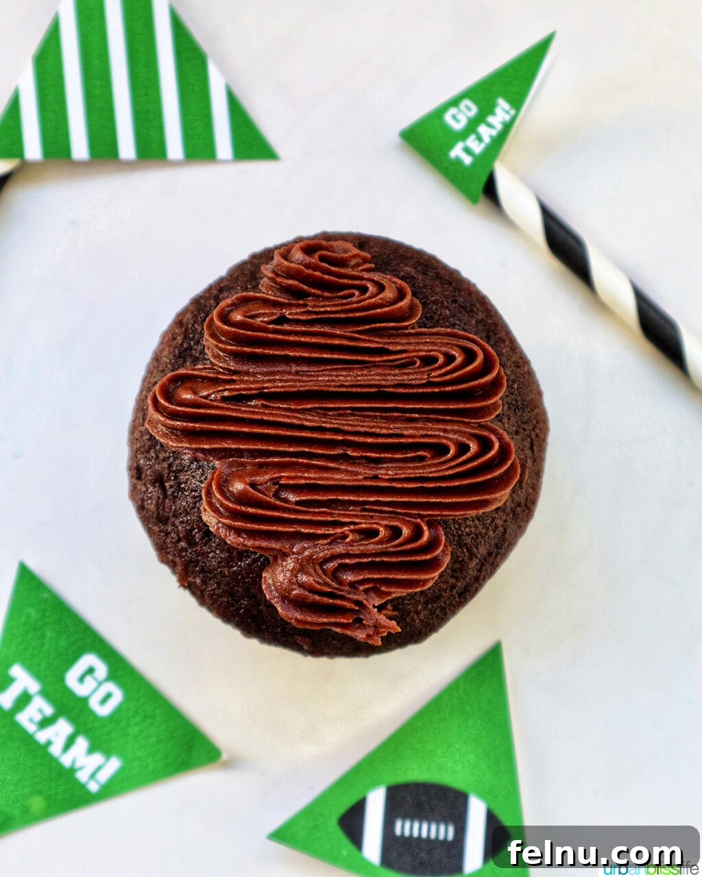 Touchdown Treats 13 First step of assembling a football cupcake, piping chocolate frosting into an oval shape.
