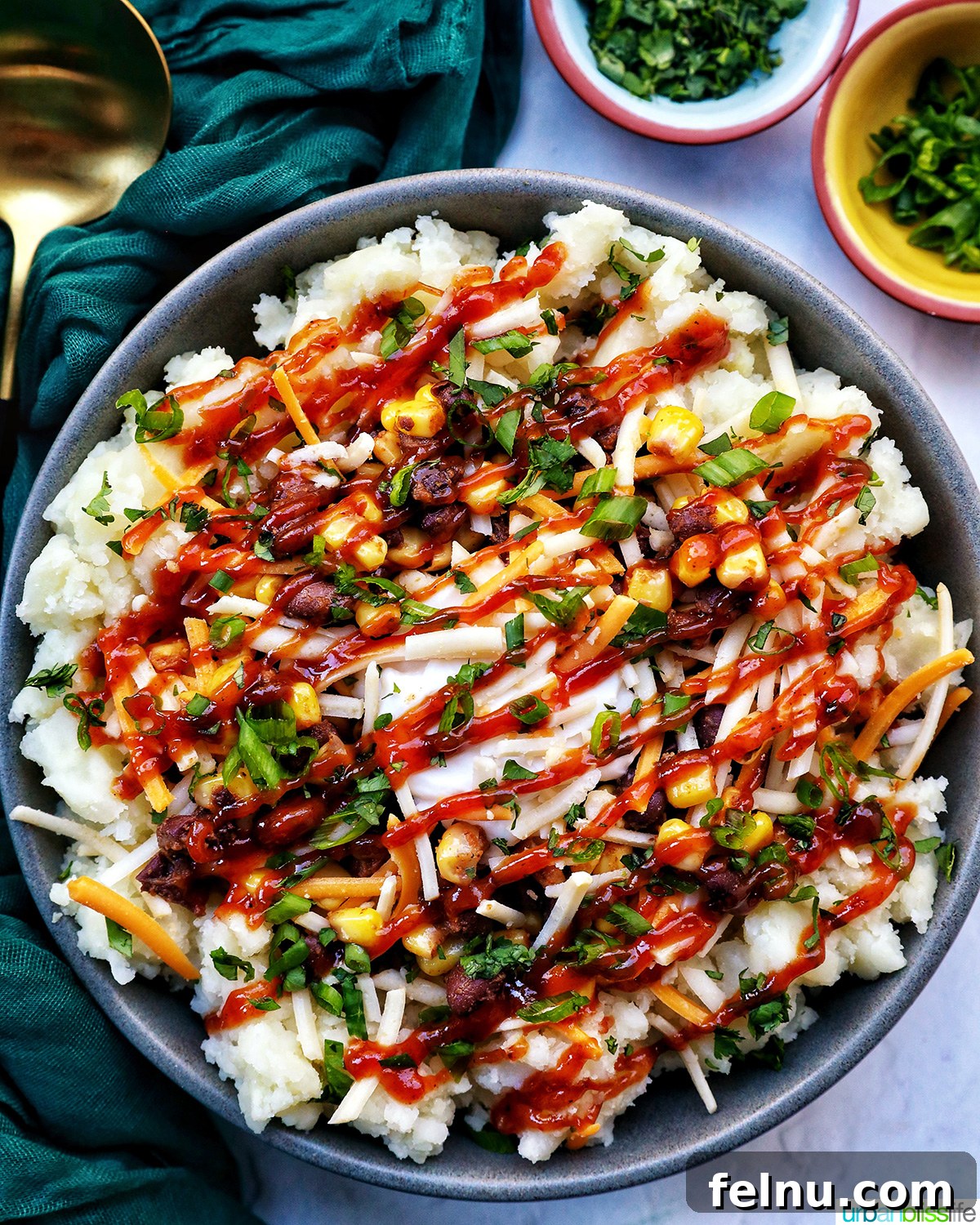 Hearty Spud Indulgence 2 A vibrant loaded potato bowl featuring fluffy mashed potatoes, black beans, sweet corn, melted cheese, and a sprinkle of fresh herbs. A spoon rests beside it, ready for a delicious bite.