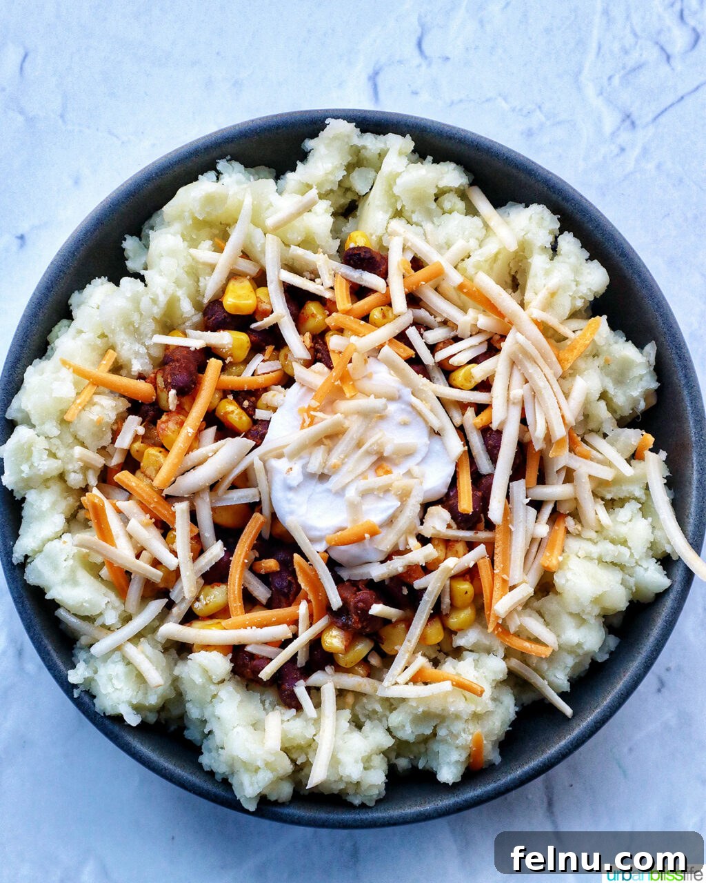 Hearty Spud Indulgence 14 A loaded potato bowl with mashed potatoes, beans, corn, and a layer of shredded cheese.