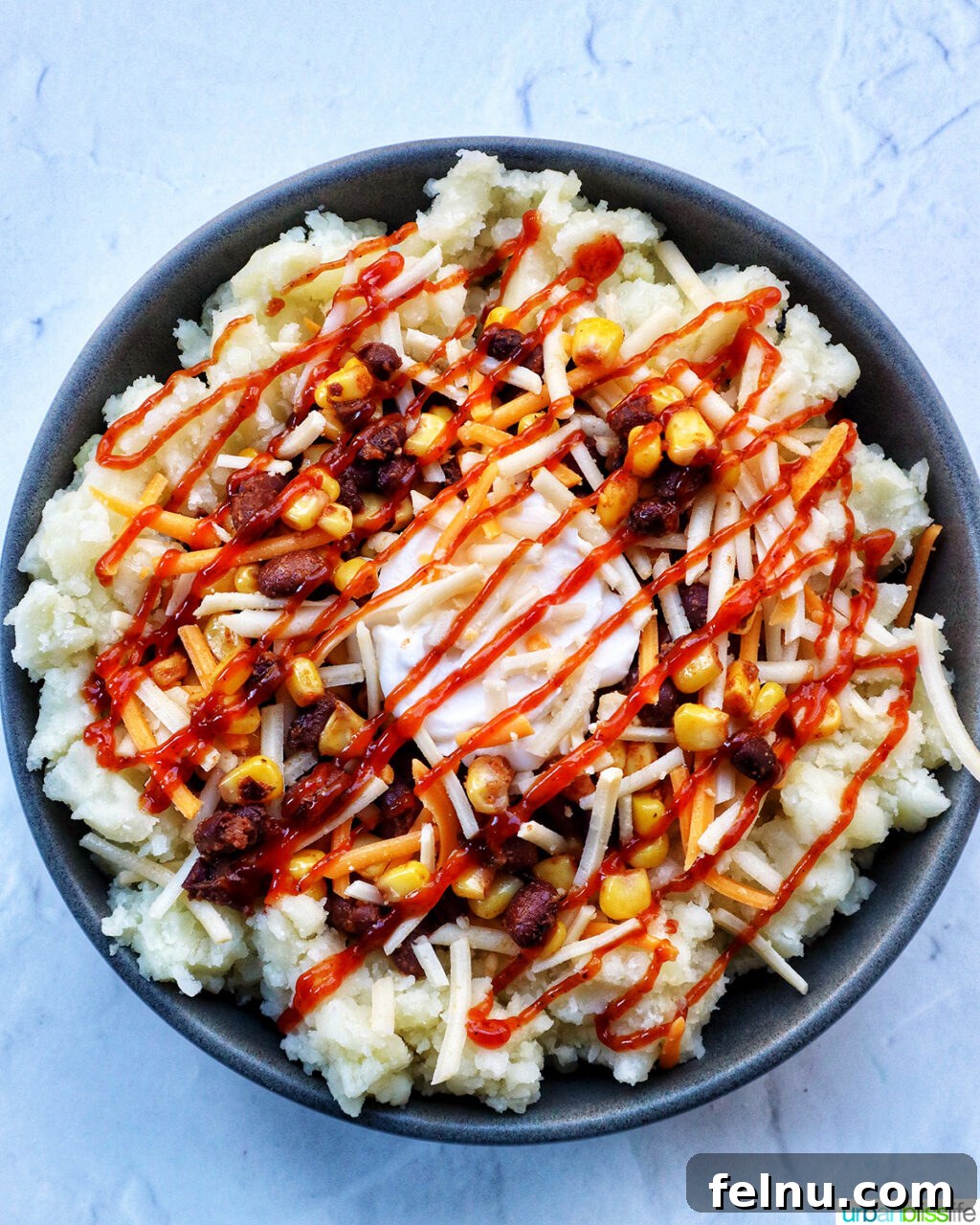 Hearty Spud Indulgence 15 A loaded potato bowl with mashed potatoes, beans, corn, cheese, and a drizzle of barbecue sauce.