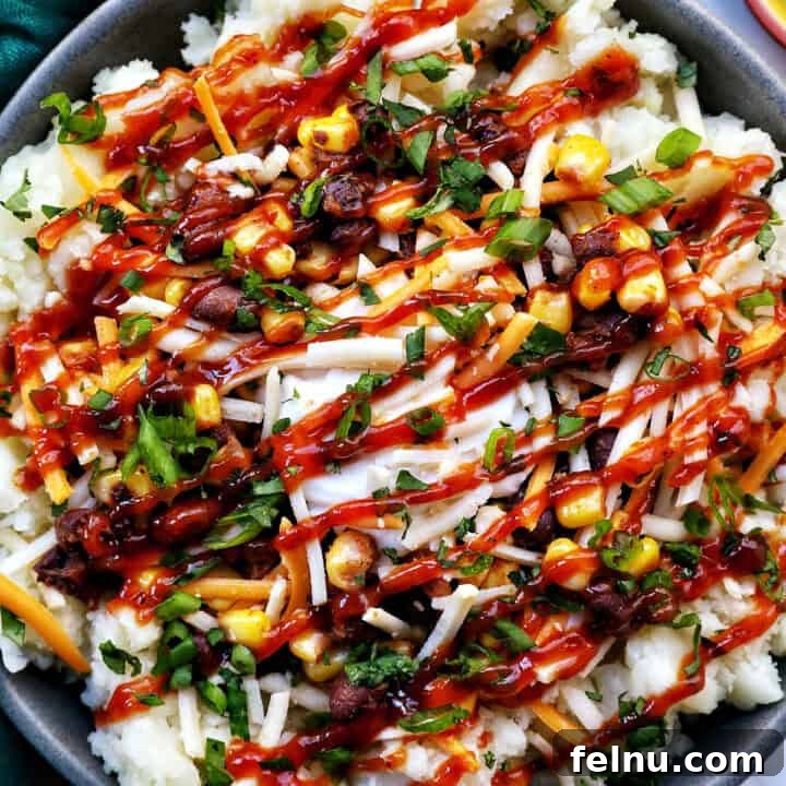 A delightful loaded potato bowl with creamy mashed potatoes, seasoned beans and corn, melted cheese, and fresh herbs.