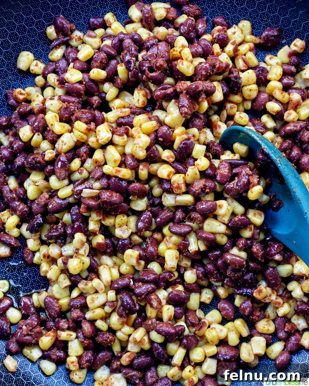 Hearty Spud Indulgence 9 The corn, black beans, and taco seasoning mixture being stirred in a hot skillet, cooking gently.
