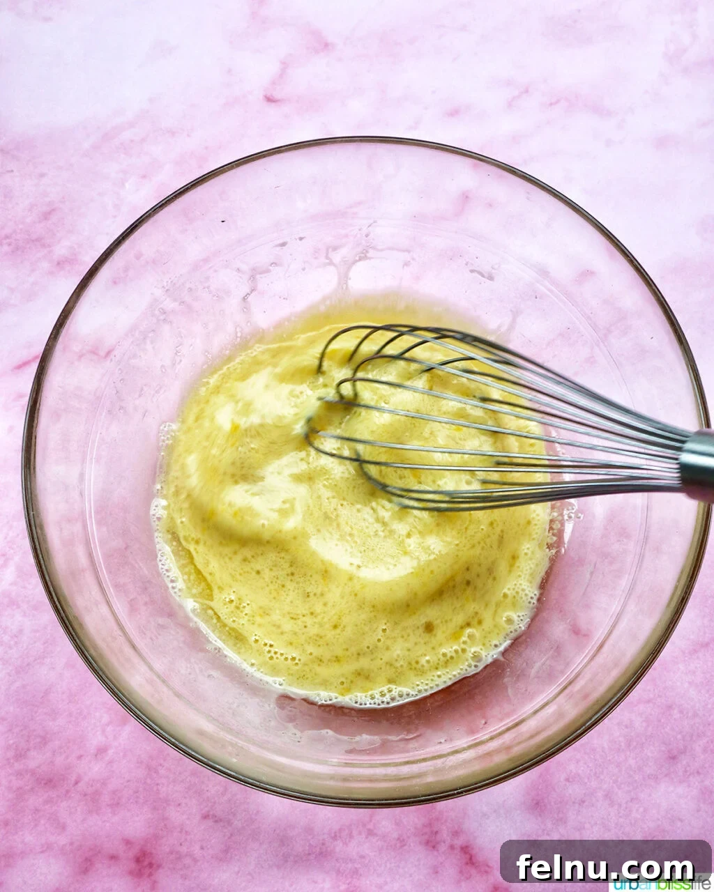 whisk whisking batter for muffins in a bowl.