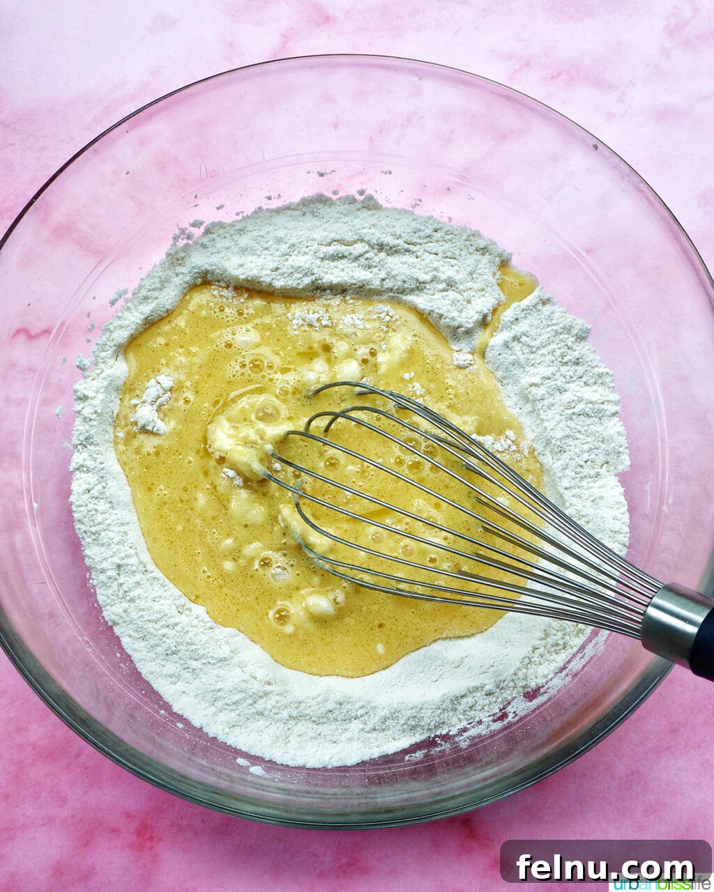 whisk whisking batter for muffins in a bowl.
