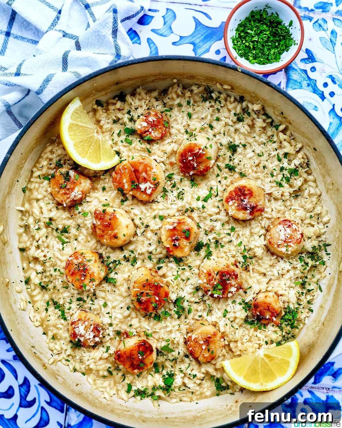 The Art of Pairing Wine with Scallops 7 braising pan with scallop risotto with lemon wedge and parsley garnish.