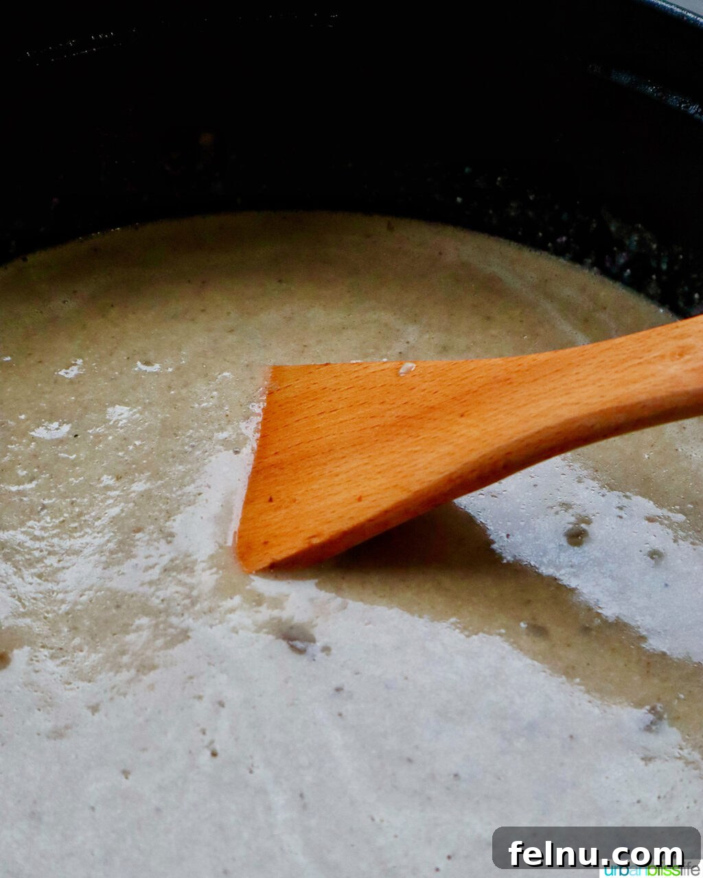 Creamy Vegan Mushroom Delight 18 A wooden spoon stirring the creamy mushroom soup in a Dutch oven.