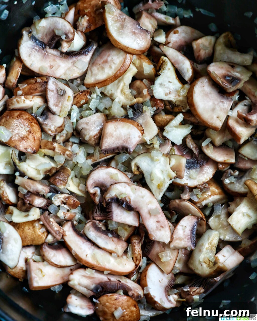 Creamy Vegan Mushroom Delight 8 Sliced mushrooms cooking with onions and herbs in a pot.