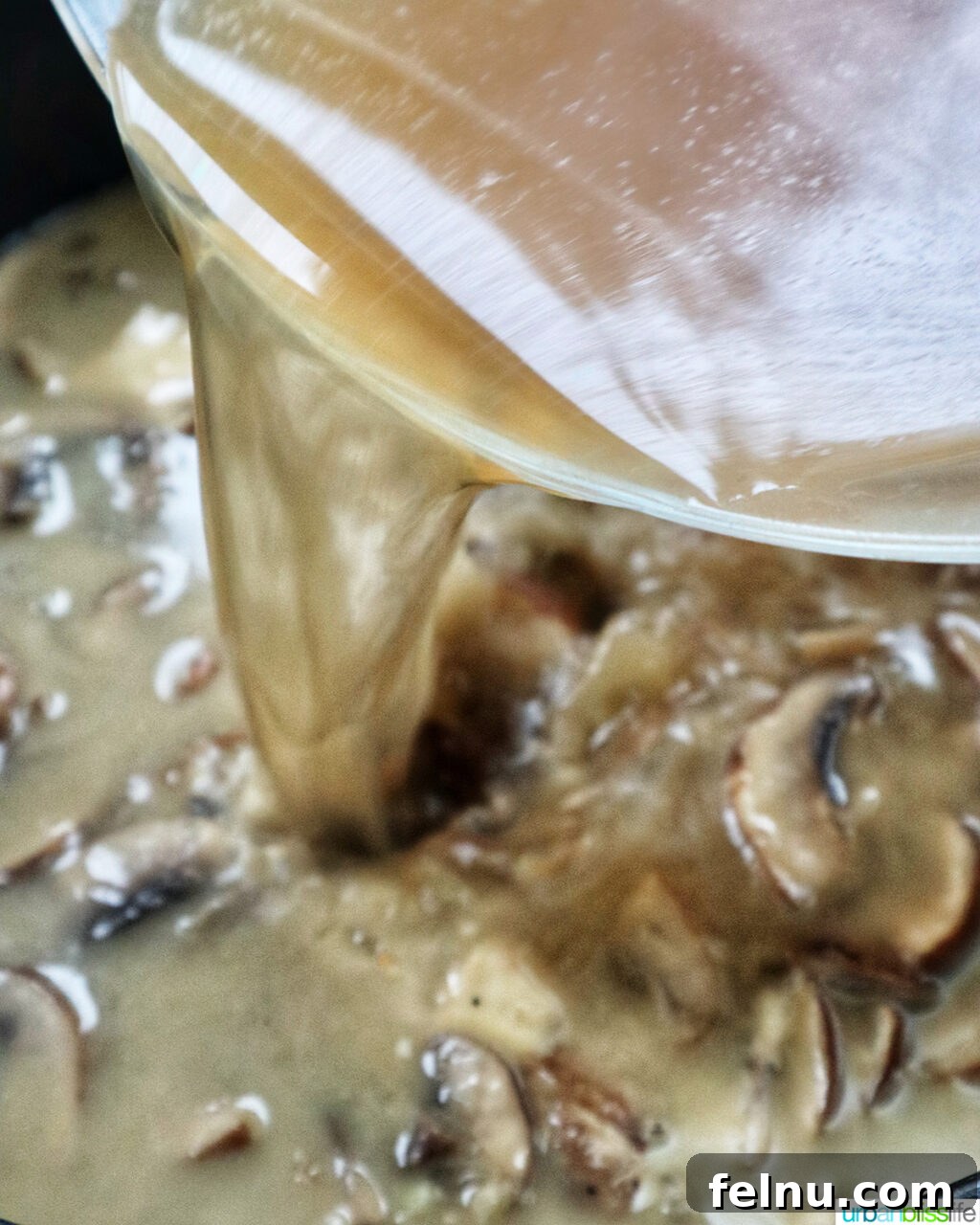 Creamy Vegan Mushroom Delight 9 Vegetable broth being poured into a pot of sautéed mushrooms and aromatics.
