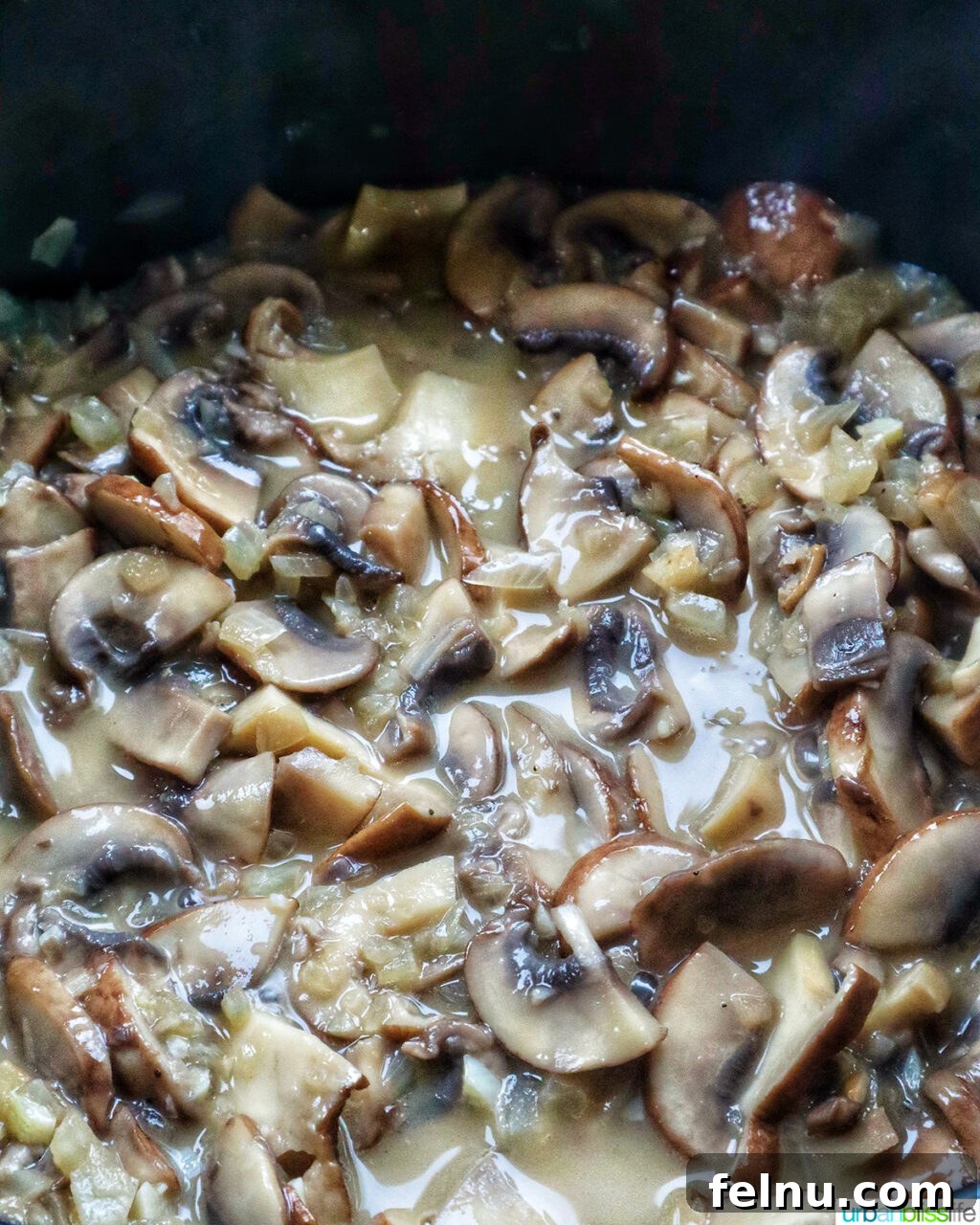 Creamy Vegan Mushroom Delight 10 Mushrooms simmering in broth in a pot.