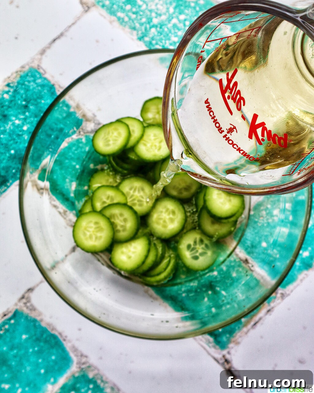 Spicy Asian Cucumber Pickles 5 pouring rice vinegar over cucumbers in a bowl.