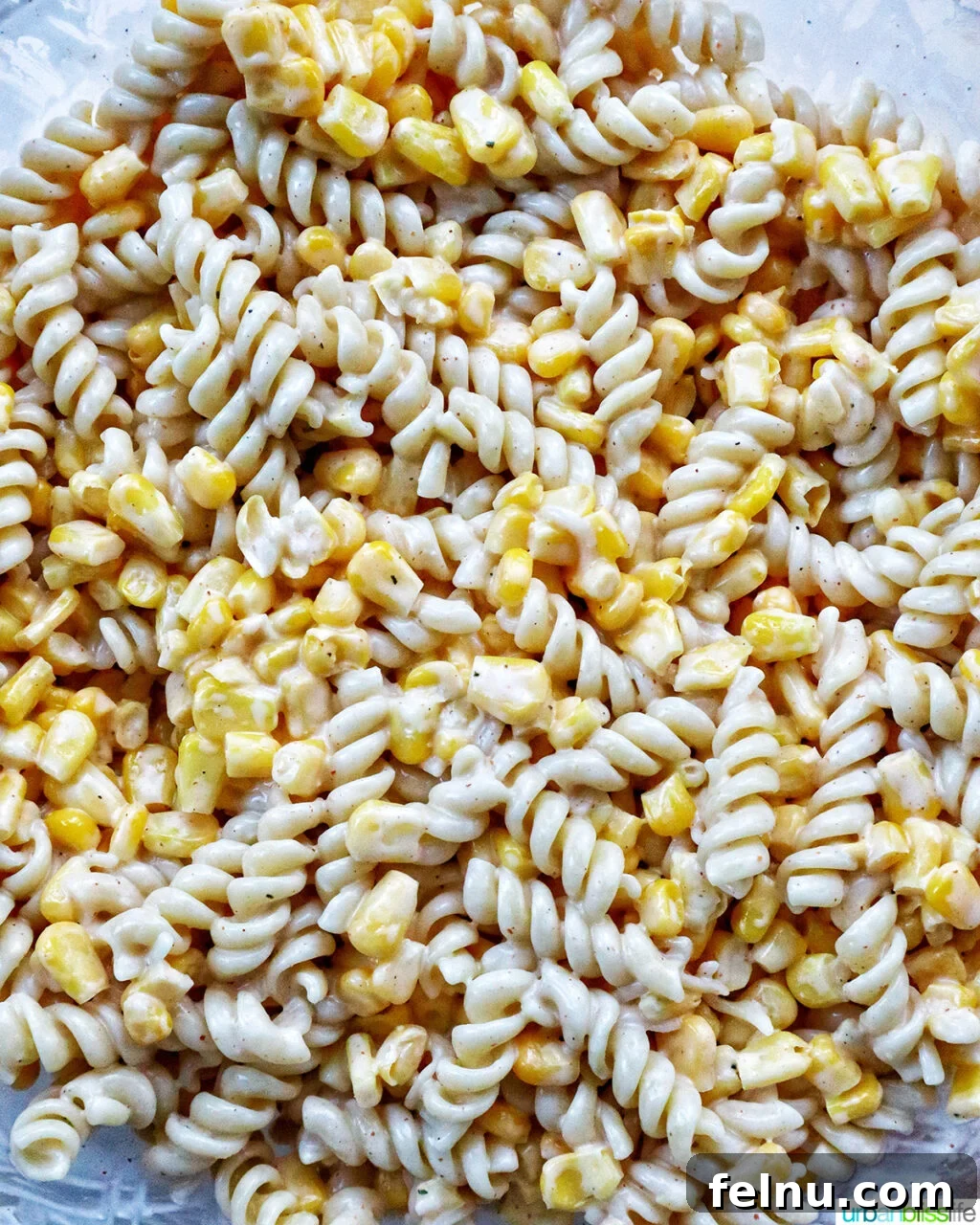 Zesty Elote Pasta Salad 12 Finely diced red onion and jalapeño being gently mixed into the pasta salad, adding color and texture.