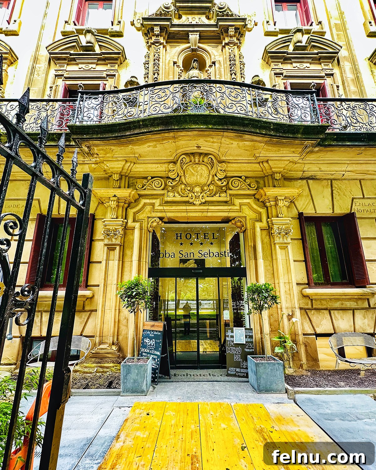The modern and inviting exterior of Abba San Sebastian hotel, featuring contemporary design and large windows, situated along a tree-lined street.