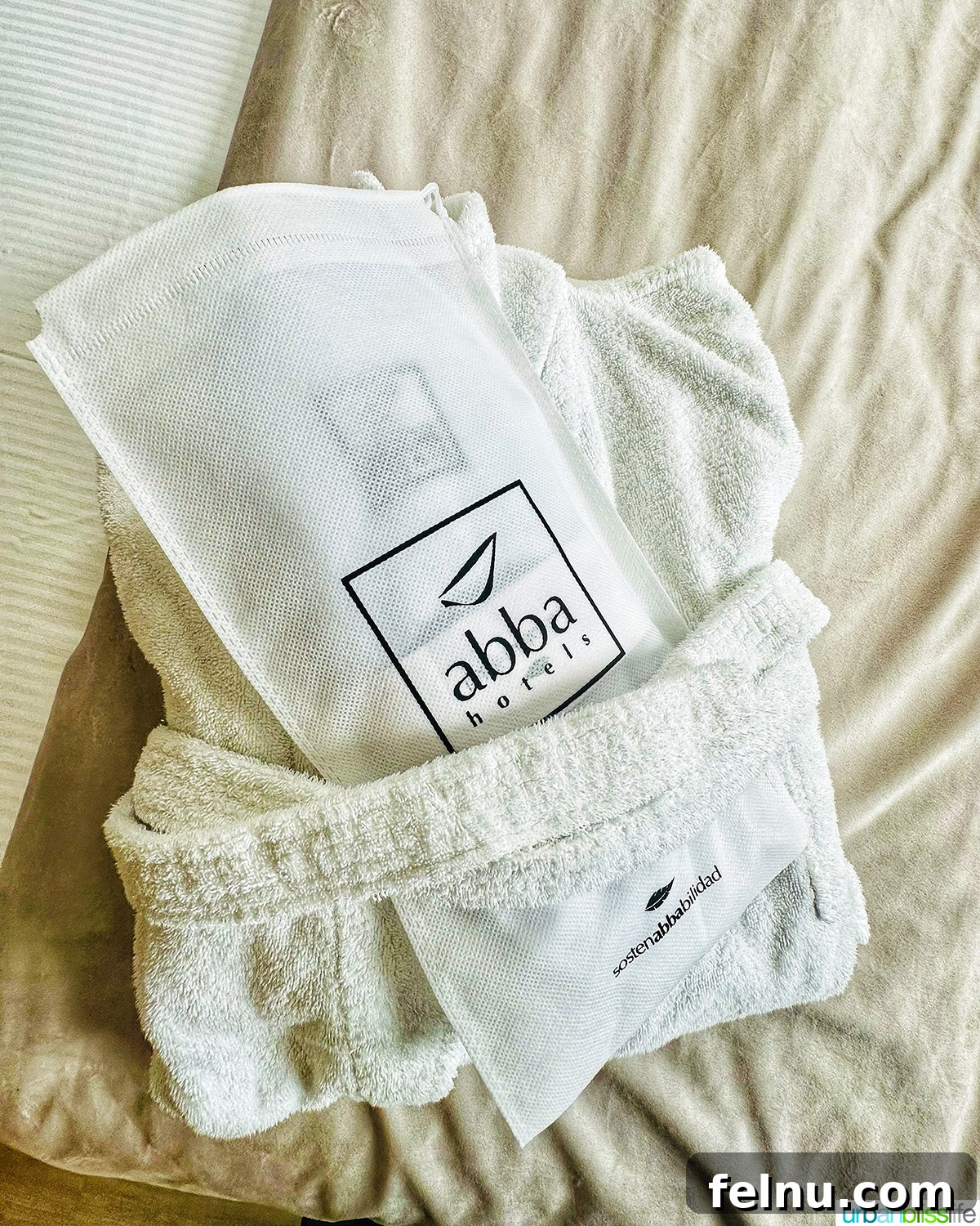 Close-up of a neatly folded bathrobe and slippers, placed invitingly on a bed in a room at Abba San Sebastian.