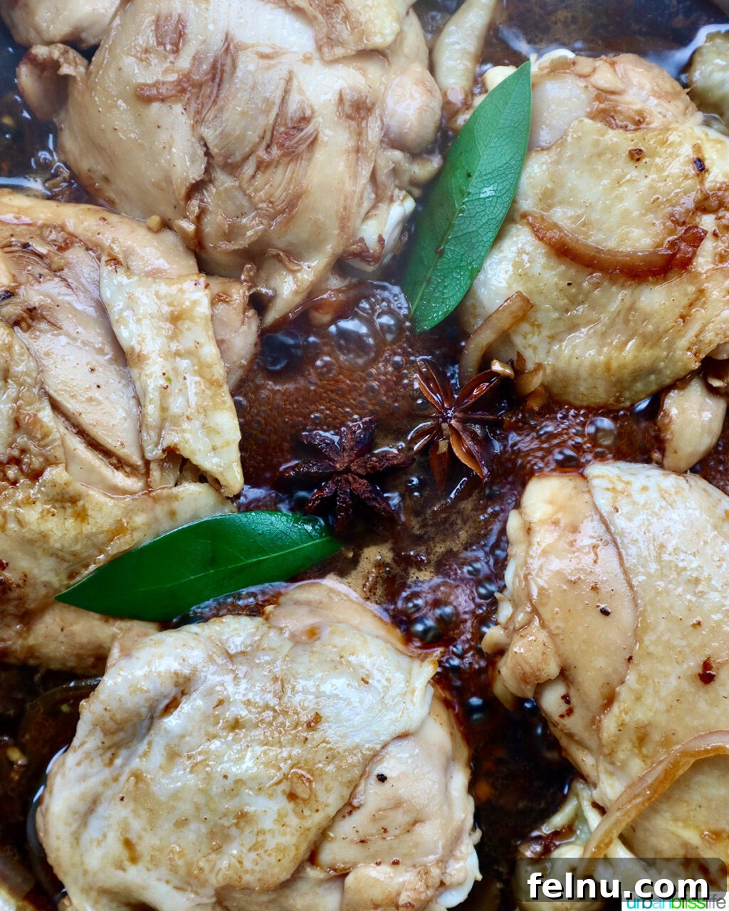 Fragrant Chinese Braised Chicken 13 Bay leaves and star anise added to chicken and sauce in a skillet.