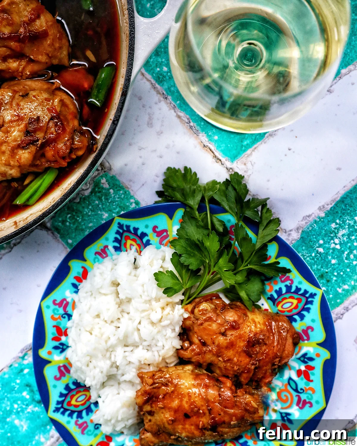 Fragrant Chinese Braised Chicken 18 Chinese braised chicken with rice on a colorful plate, accompanied by a glass of white wine.
