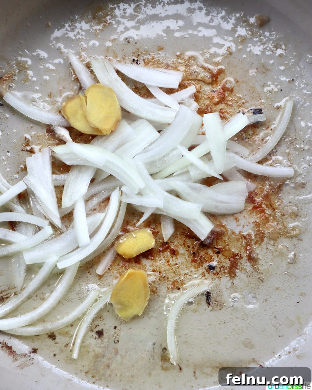 Fragrant Chinese Braised Chicken 8 Sliced onions and ginger sautéing in a skillet.