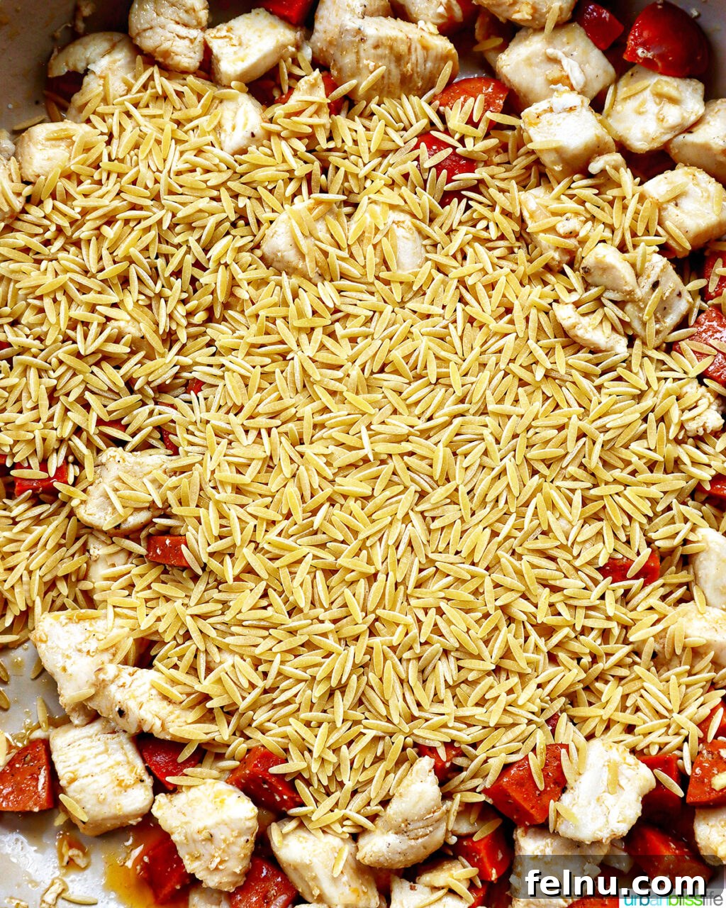 Chicken and Chorizo Orzo Skillet 10 orzo added to a pan of chicken and chorizo