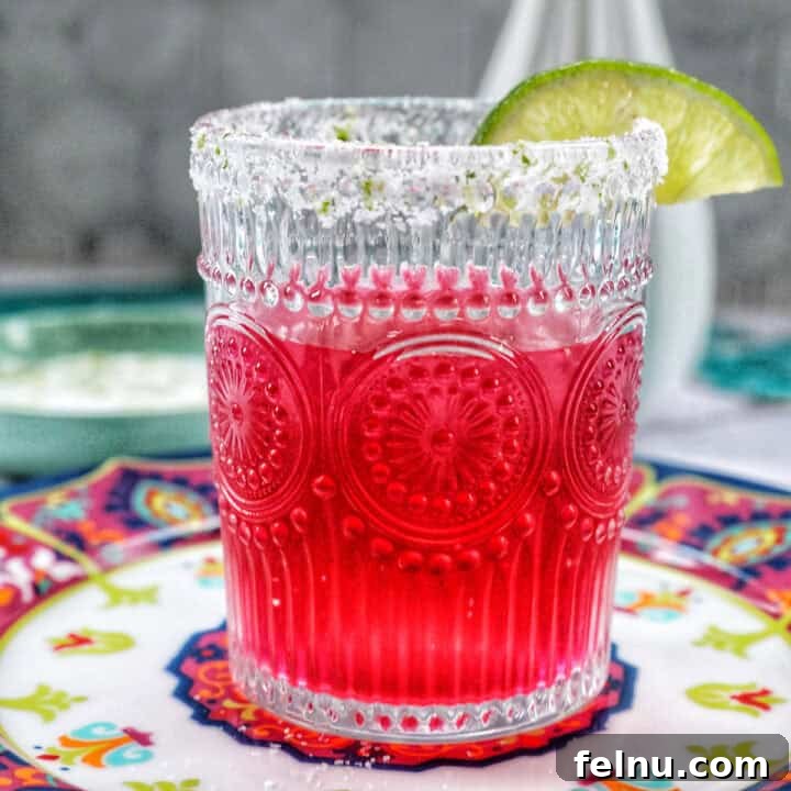Glass of prickly pear margarita with lime slice garnish.