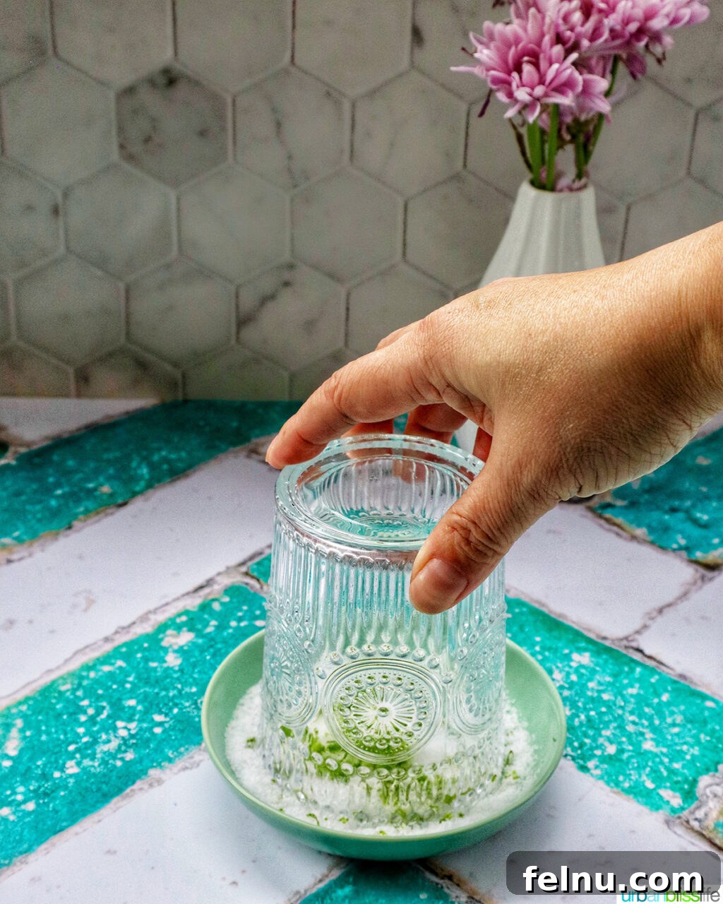 Desert Bloom Margarita 6 Hand holding a cocktail glass upside down over a shallow bowl of lime salt to coat the rim.