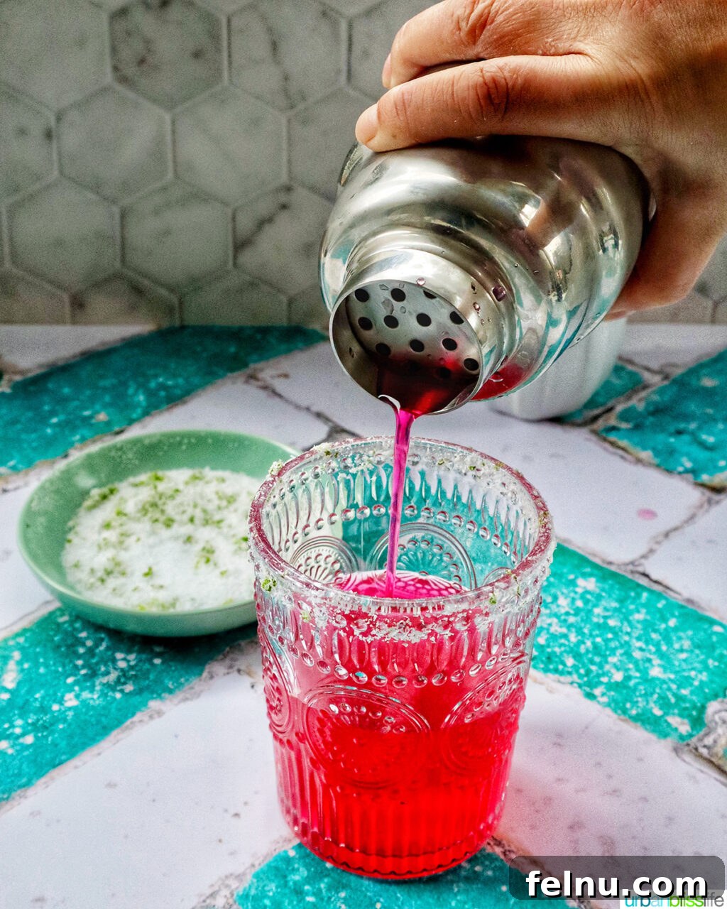 Desert Bloom Margarita 9 Pouring a vibrant prickly pear margarita from a cocktail shaker into a prepared glass.