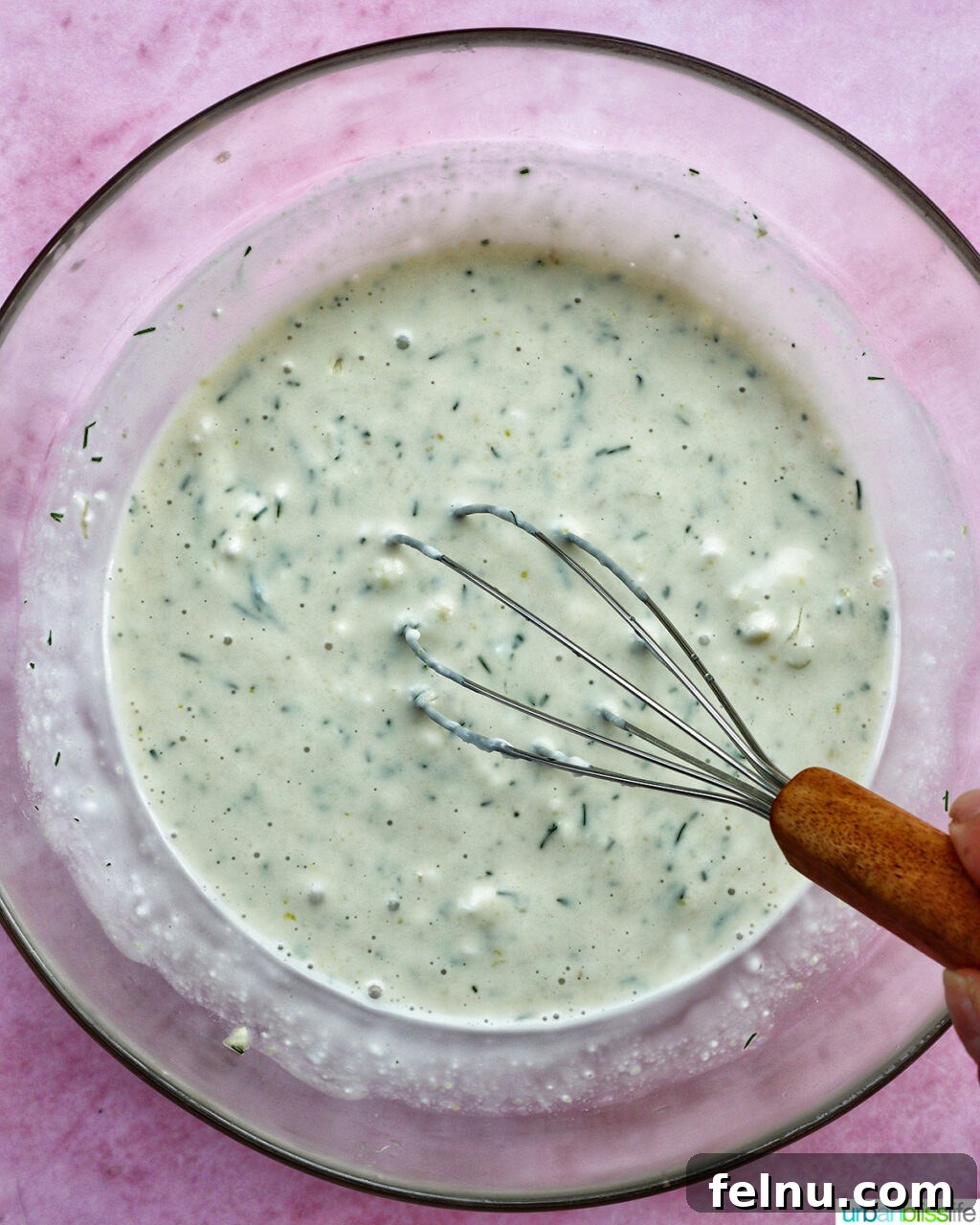 Whisk with dressing in a bowl