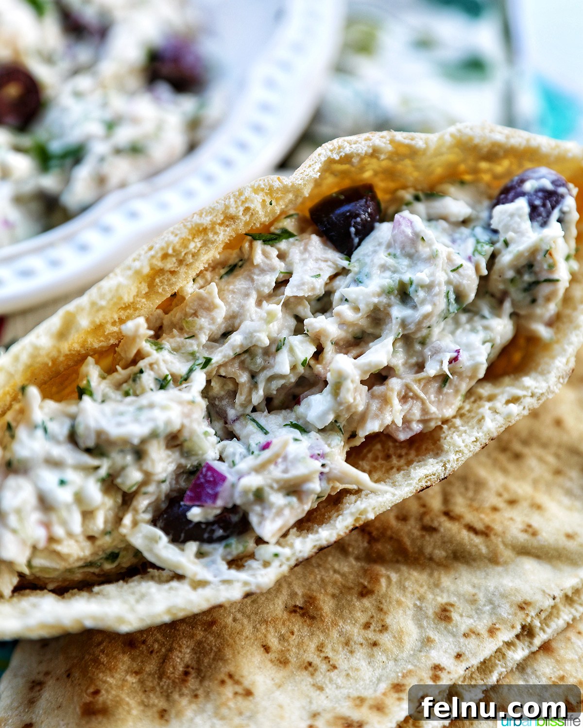 Cool & Creamy Tzatziki Chicken Salad 2 A vibrant Tzatziki Chicken Salad served inside a freshly baked bread roll, garnished with fresh herbs.