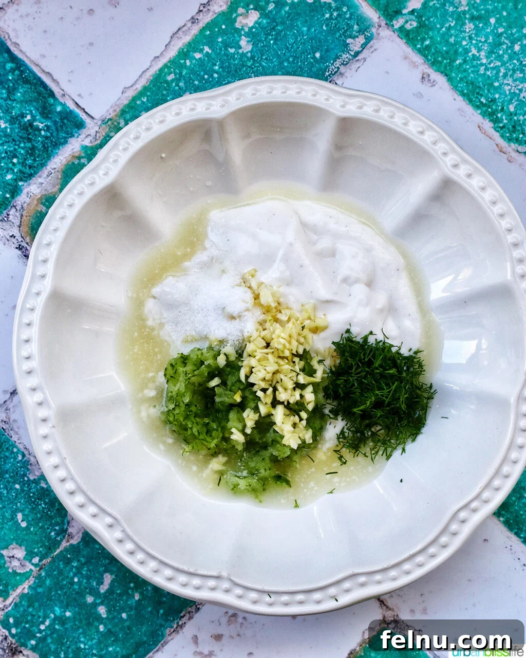 Cool & Creamy Tzatziki Chicken Salad 5 Step 1: In a bowl, Greek yogurt, grated cucumber, lemon juice, and minced garlic are mixed to form the tzatziki base.