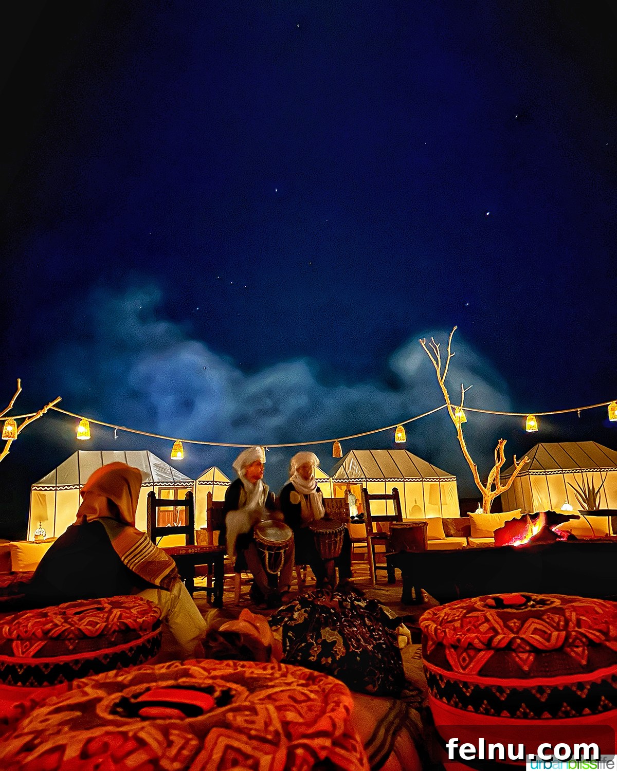 Morocco's Sahara Desert Adventure Guide 9 Berber musicians playing traditional instruments around a campfire at a luxury desert camp at night in the Sahara Desert in Morocco.
