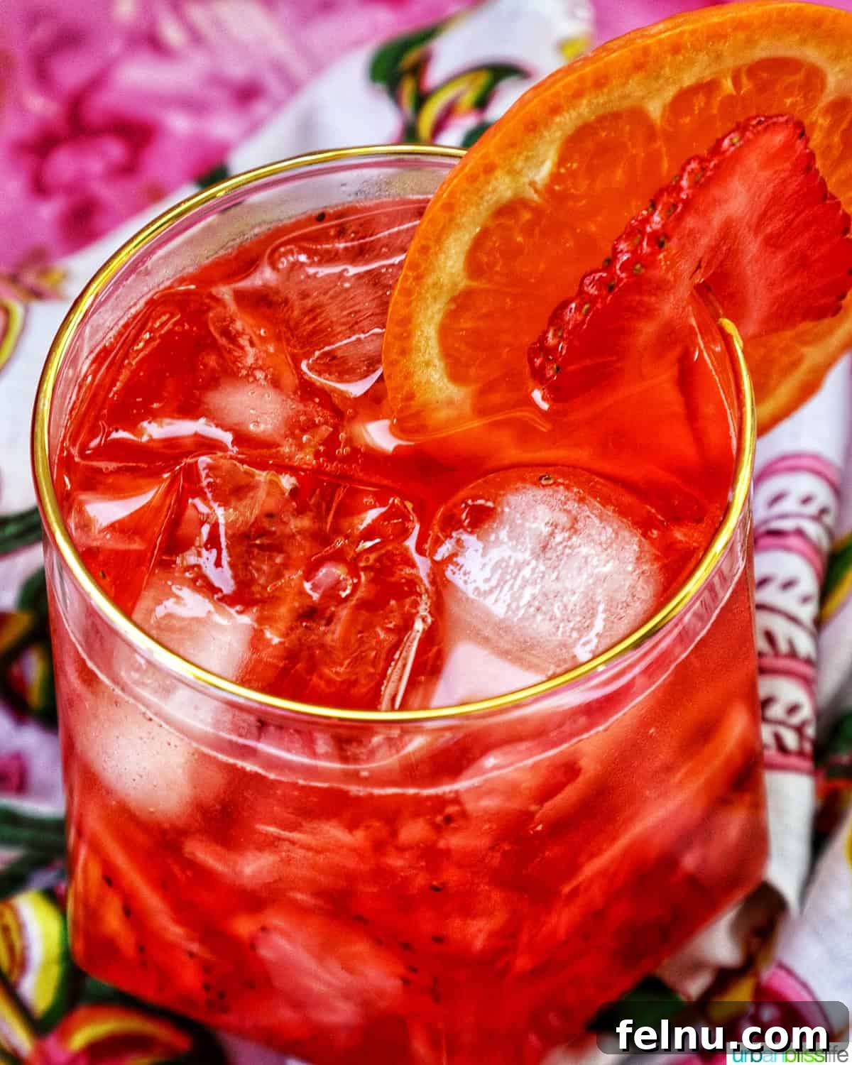 Close-up of a Strawberry Spritz with orange and strawberry garnish.