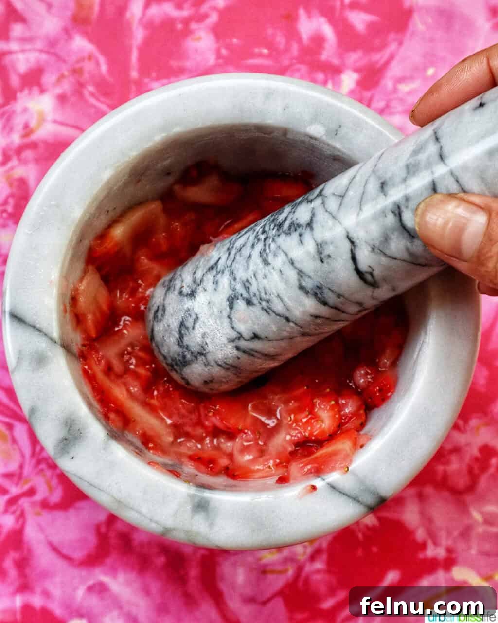 Muddling fresh strawberries in a mortar and pestle.