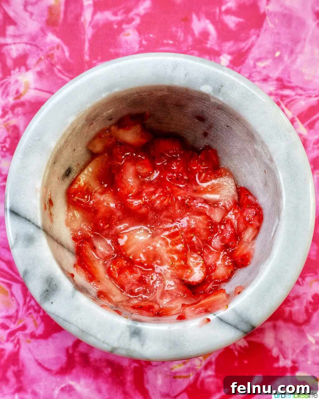 Close-up of muddled strawberries in a mortar and pestle.
