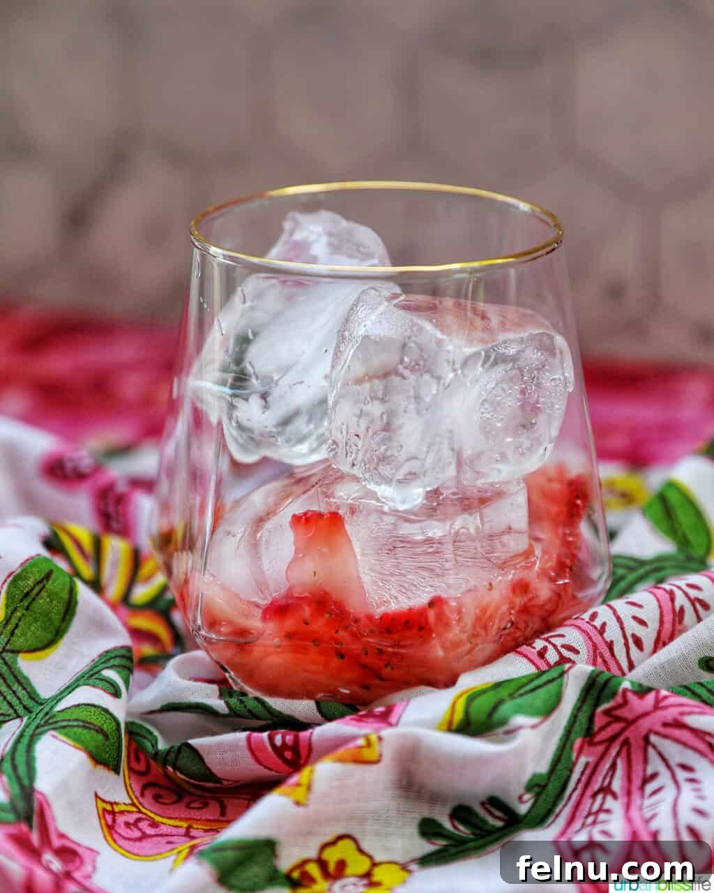 A glass filled with ice and muddled strawberries.