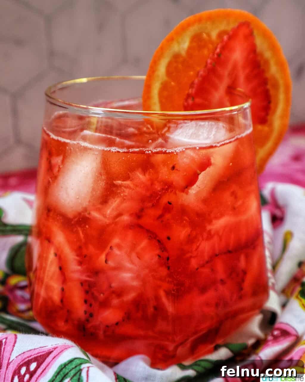 Finished Strawberry Spritz with orange and strawberry garnish.
