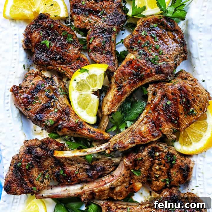 Aegean Lamb Chops 11 Greek lamb chops on a white plate with herbs and lemon slices.