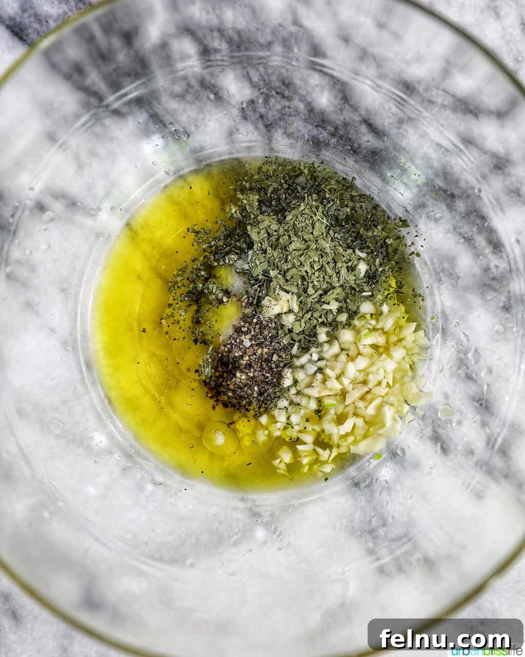 Aegean Lamb Chops 5 Bowl with olive oil, herbs, and lemon juice mixed for lamb marinade.