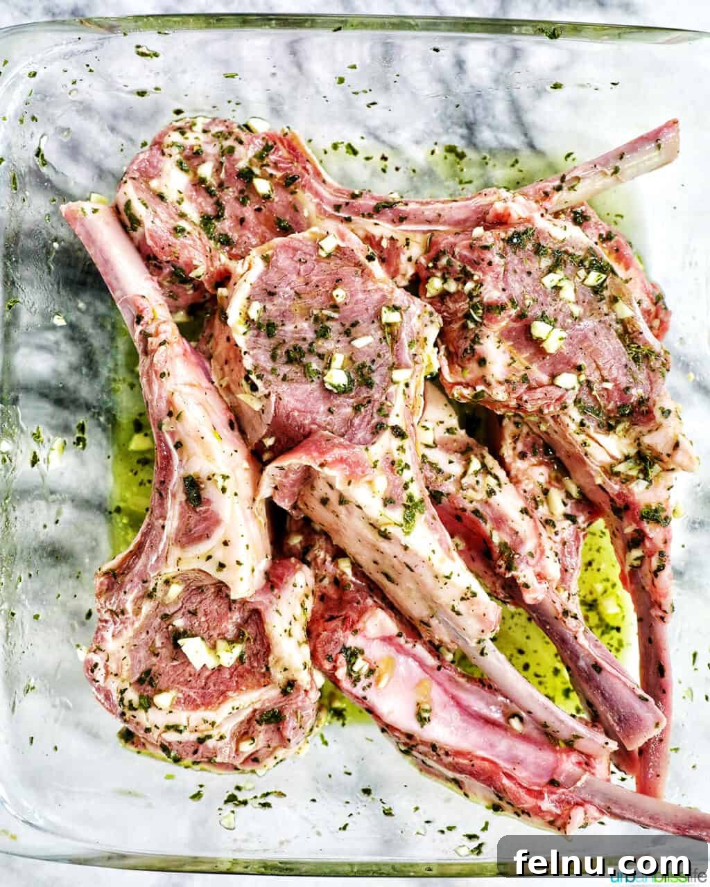 Aegean Lamb Chops 6 Lamb chops marinating in a bowl, covered.