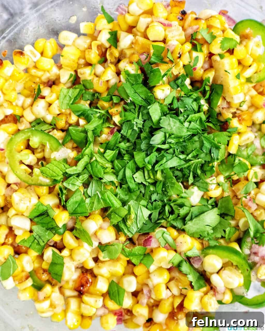 Fire-Kissed Corn Salad 11 Freshly chopped cilantro, mint, and parsley being added to charred corn kernels in a bowl.