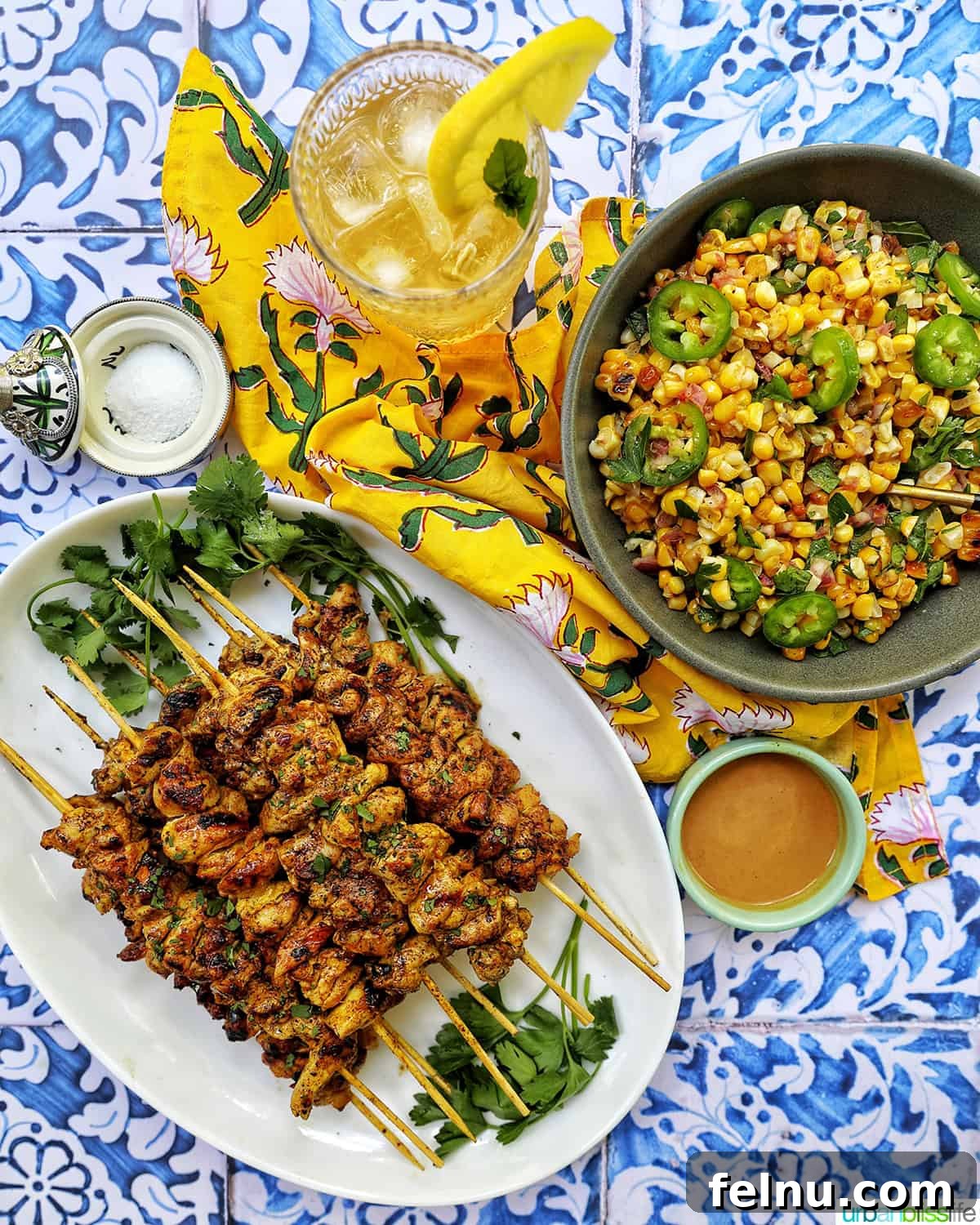 Fire-Kissed Corn Salad 14 A summer meal spread featuring charred corn salad, tandoori chicken skewers, and a glass of bourbon lemonade.