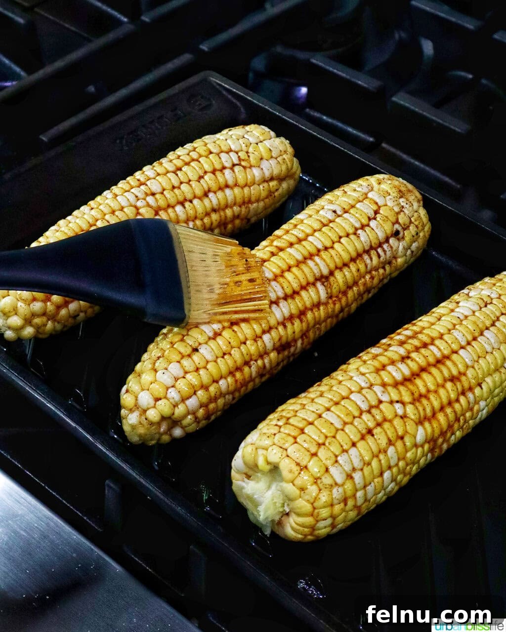 Fire-Kissed Corn Salad 7 Corn on the cob being basted with marinade on a grill pan.