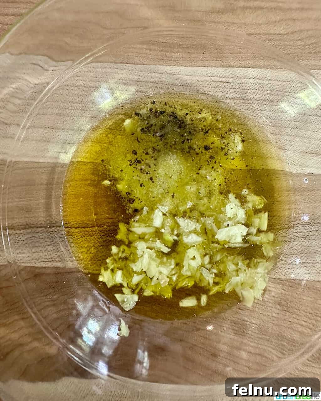 Bowl of olive oil, garlic, and seasonings mixed together.