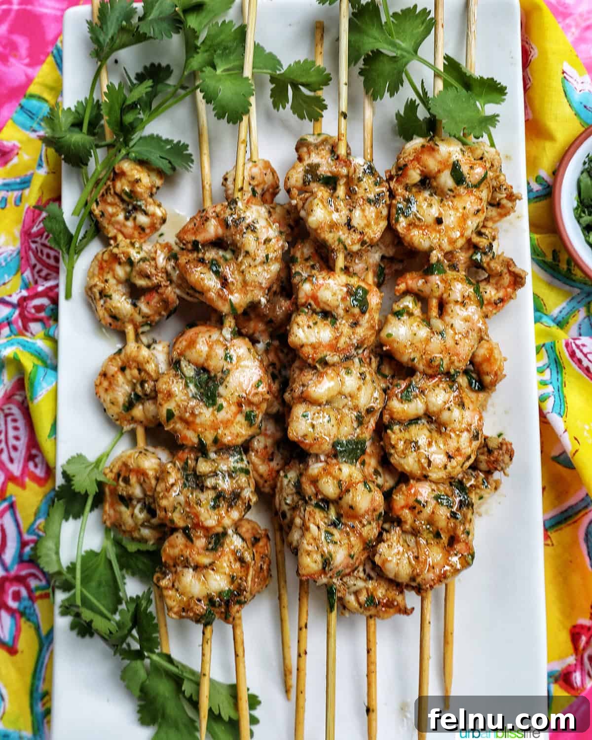 Grilled Shrimp Skewers with Chili-Lime Glaze 10 Prawn BBQ Skewers on a white plate with a fresh herb garnish.