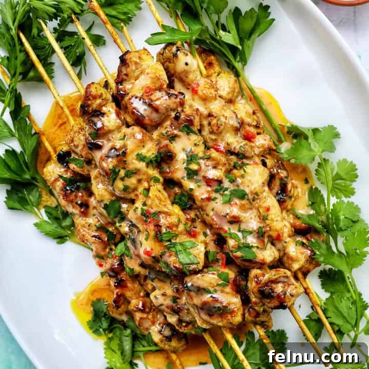 Spicy Peanut Glazed Chicken Skewers 16 Bang Bang Chicken Skewers on a plate with herb garnish, ready to be served.