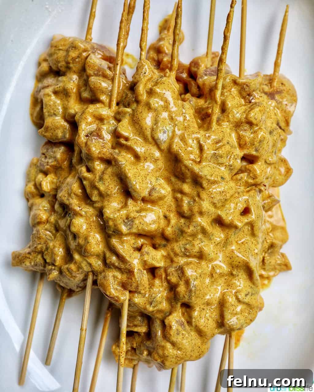 Spicy Peanut Glazed Chicken Skewers 7 Marinated chicken pieces perfectly threaded onto wooden skewers, arranged on a plate.
