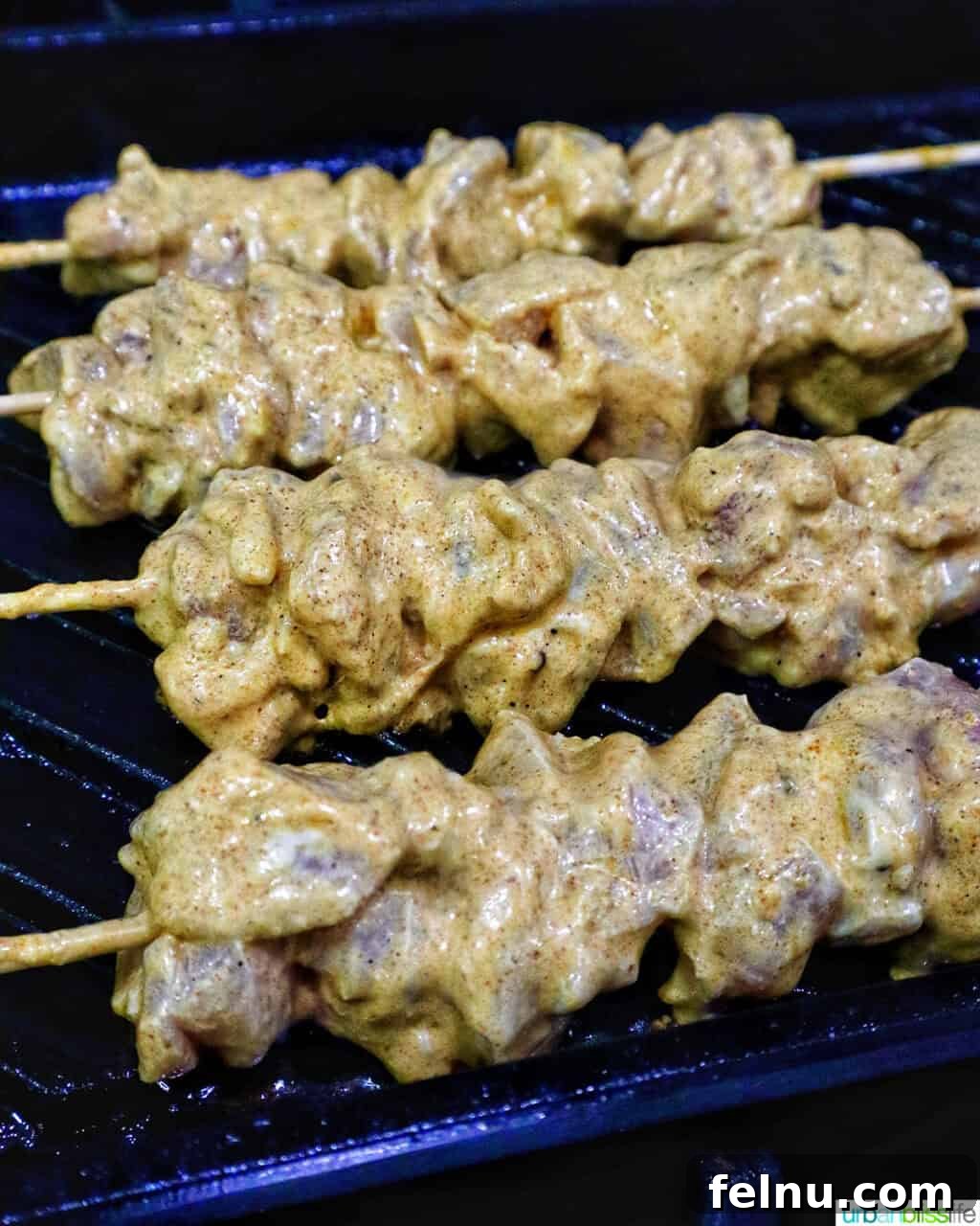Spicy Peanut Glazed Chicken Skewers 8 Bang Bang Chicken Skewers sizzling and cooking on a ridged grill pan.